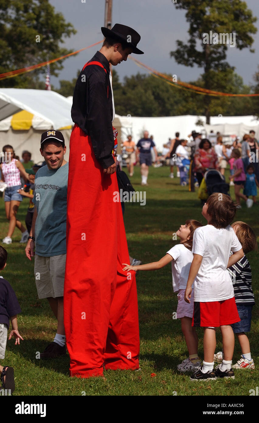A man on stilts with a child looking up at him at a fair festival Stock Photo