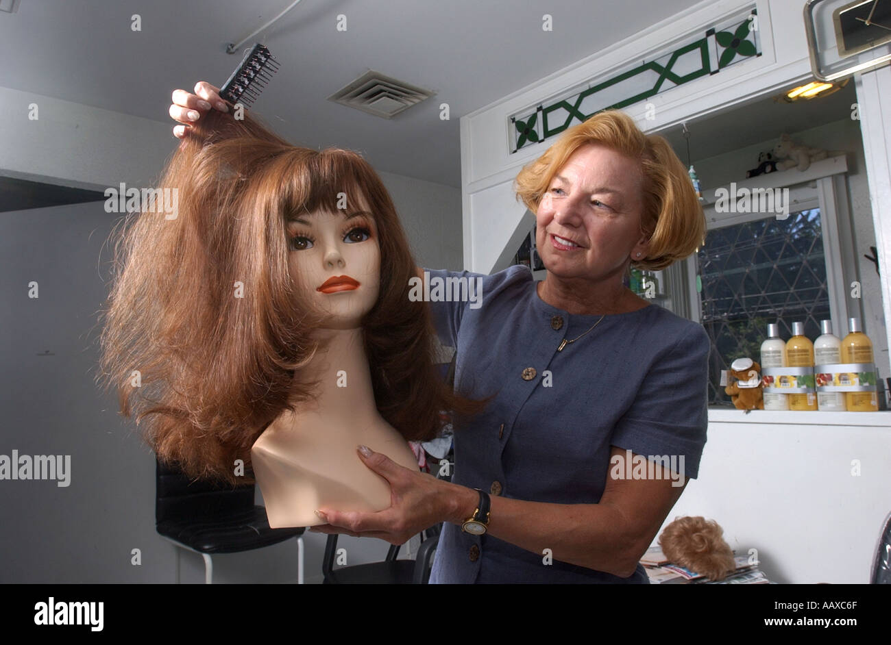 woman who specializes in making wigs for people with hair loss due to cancer or illness holding a wig Stock Photo