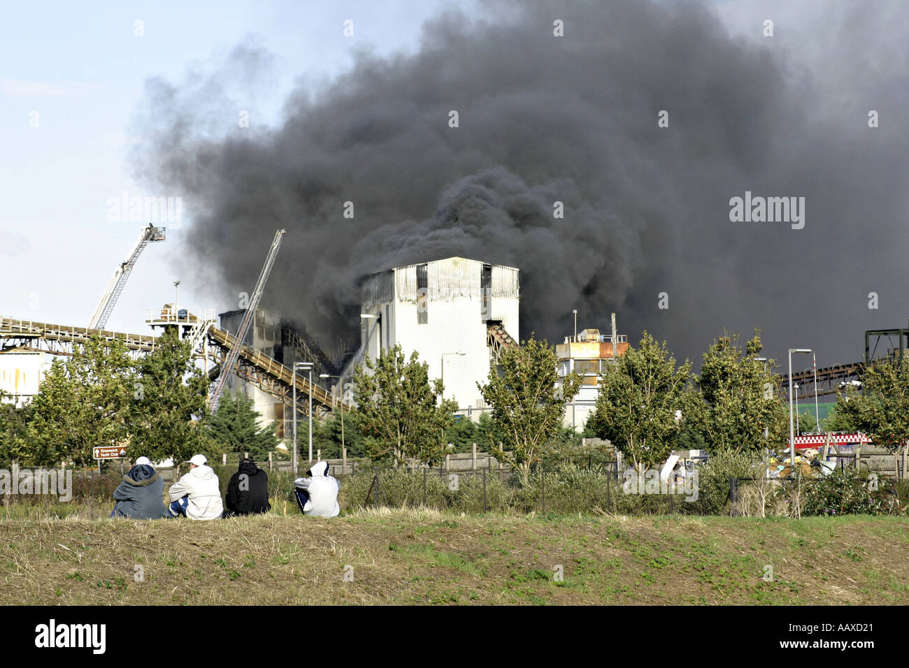 factory fire burning smoke black clouds toxic chemicals fumes pollution gas environment old disrepair decrepid decrepit city urb Stock Photo
