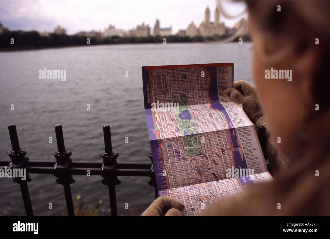Woman reading map in Central Park New York with reservoir in view Stock Photo