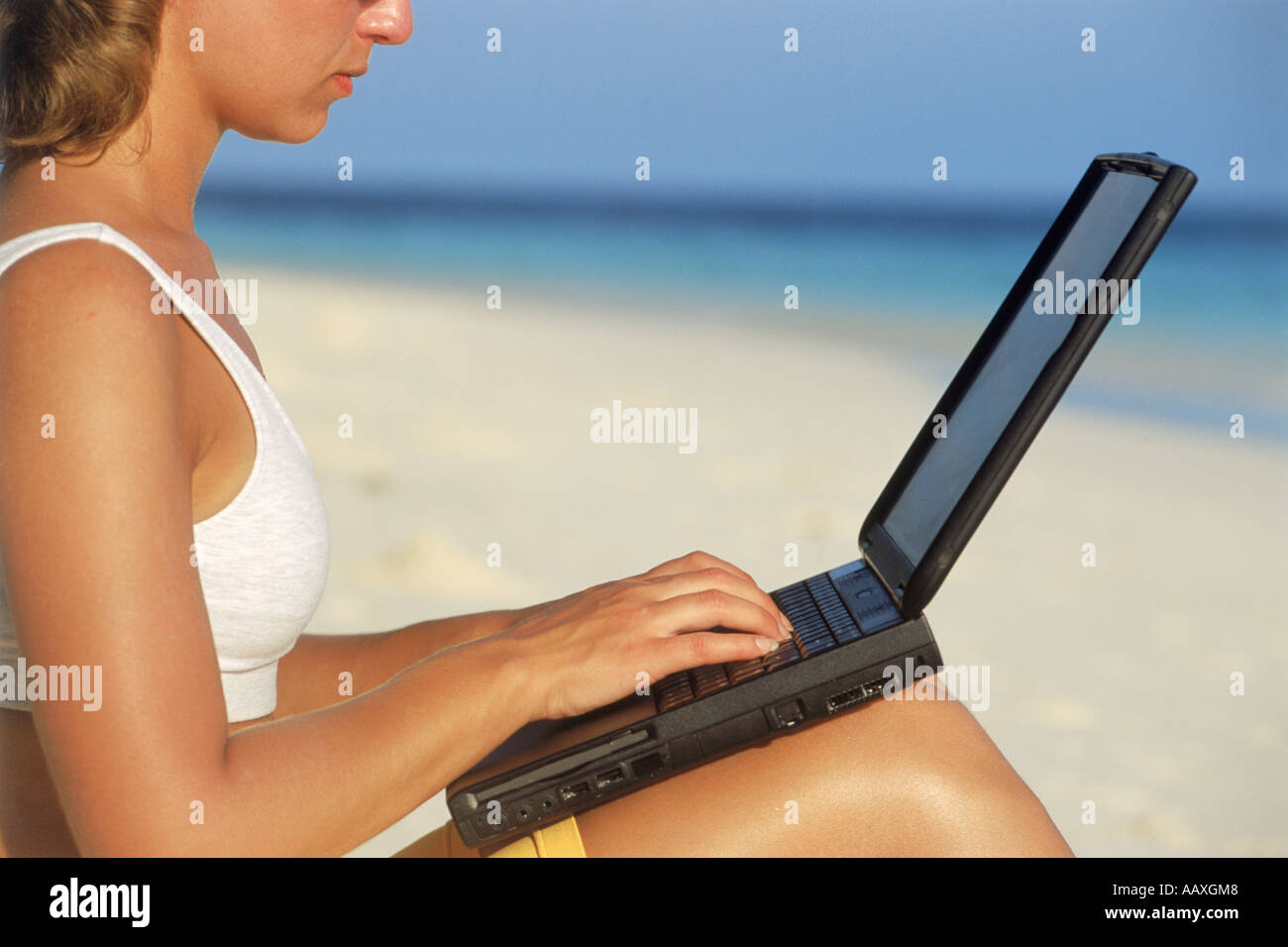 Woman on beach using laptop during working holiday Stock Photo