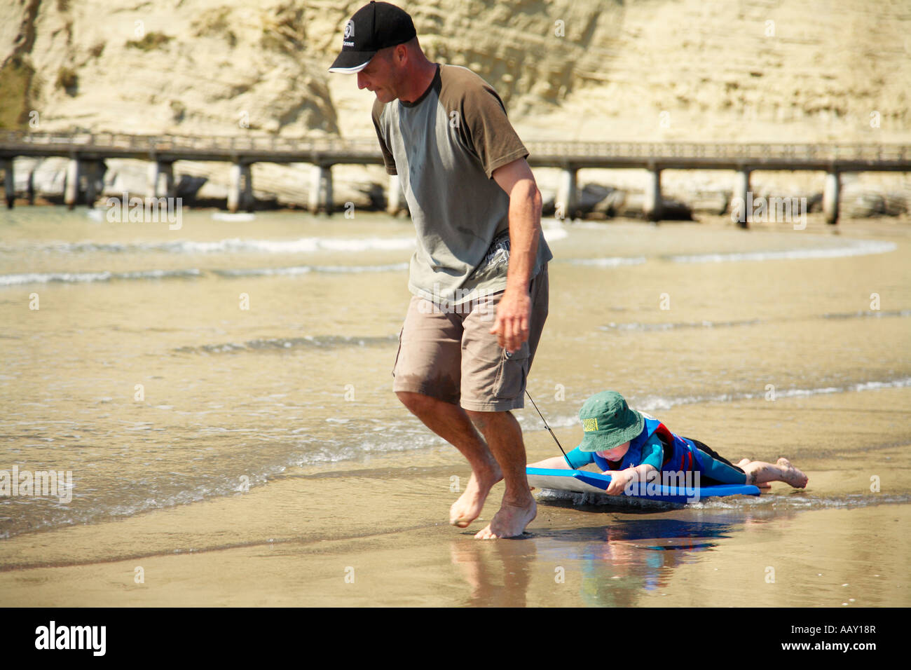 man-pulling-a-child-around-on-body-board-at-the-beach-AAY18R.jpg