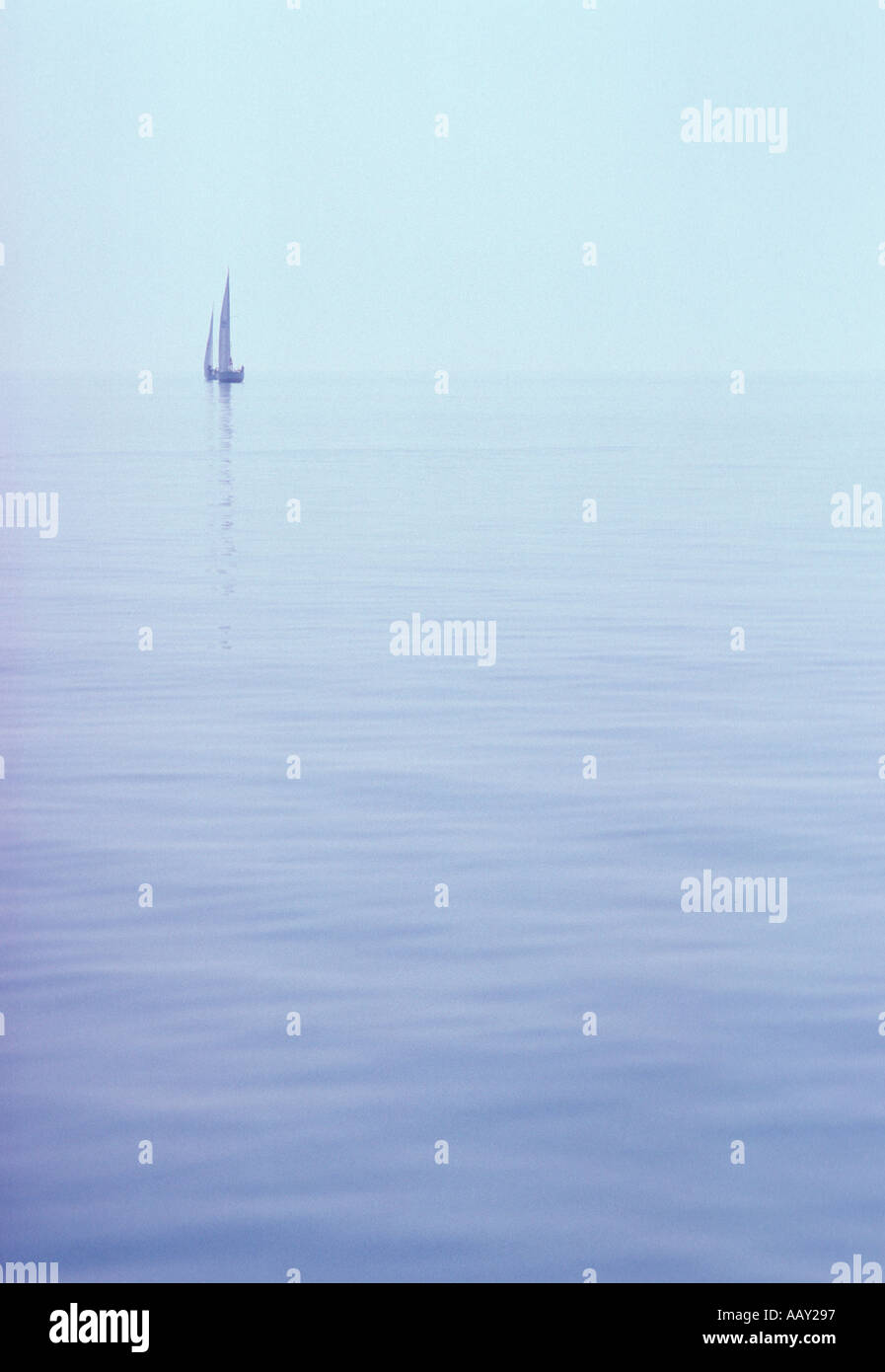 Becalmed sailboat near the misty horizon Stock Photo