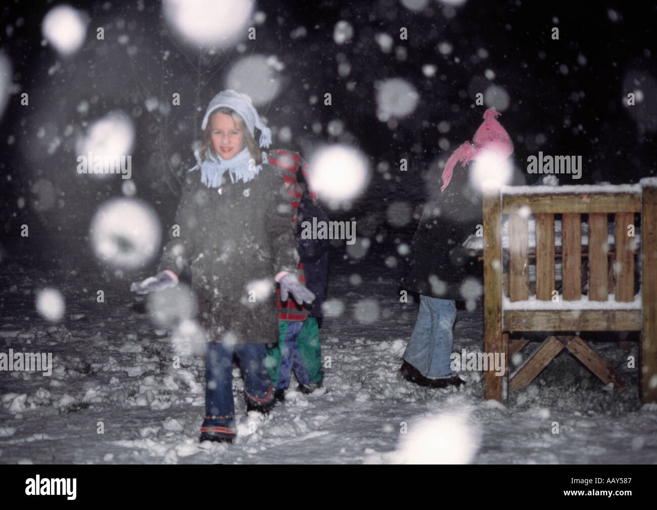children playing outside in the snow in the dark Stock Photo