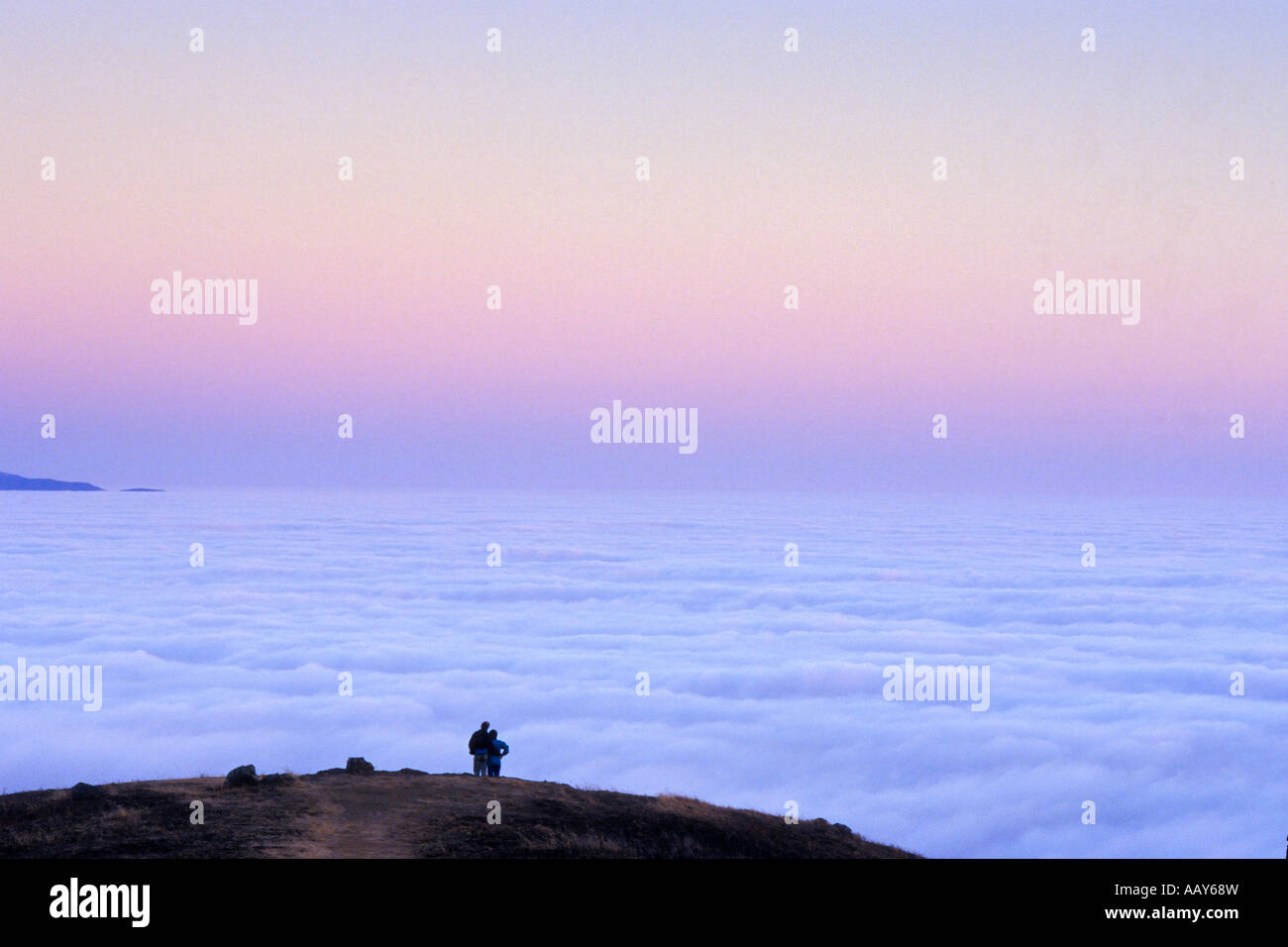 happy couple walking hand in hand on mountain above the fog watching ...