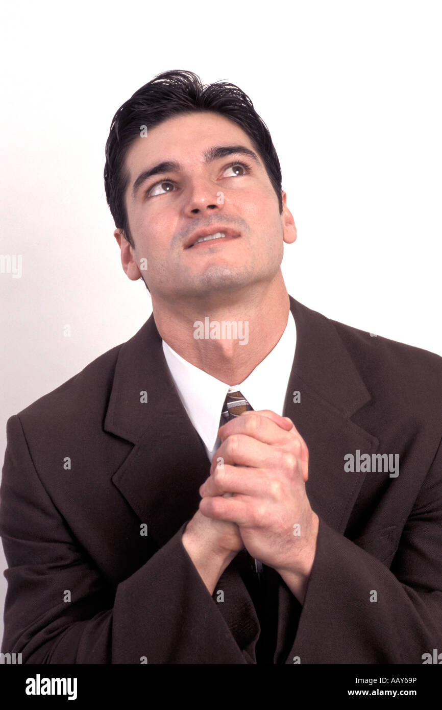 hopeful businessman saying prayers asking for help looking up to the heavens wishing and praying Stock Photo