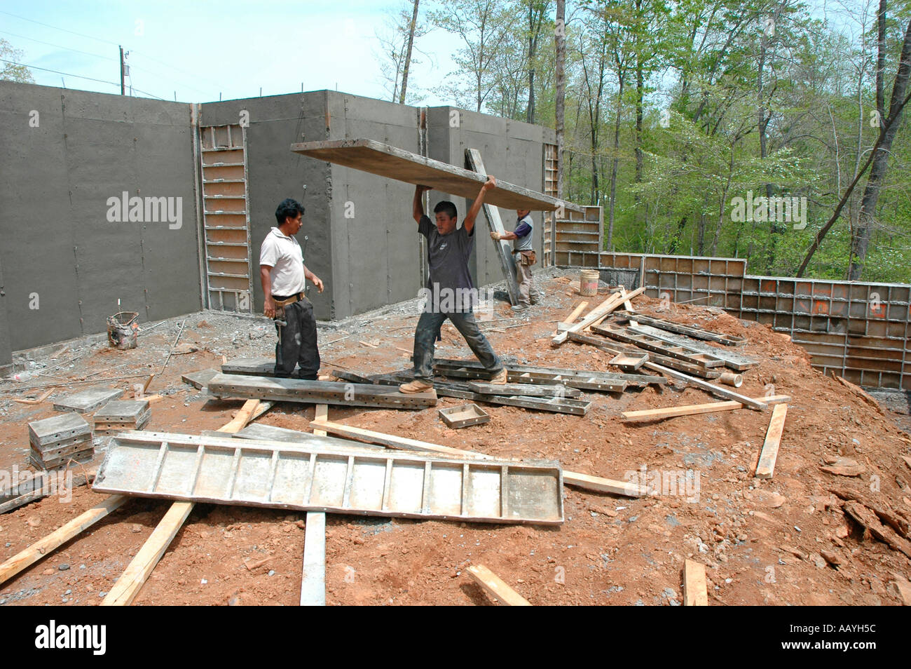 Putting in Cement footings for walls of new house by Latin labor laborers with delivery truck