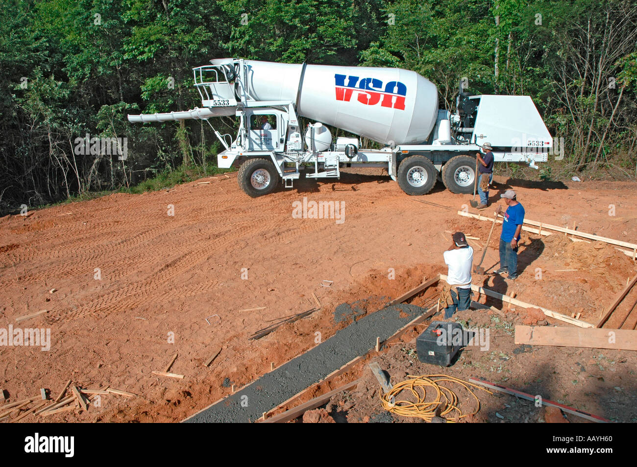 Putting in Cement footings for walls of new house by Latin labor laborers with delivery truck