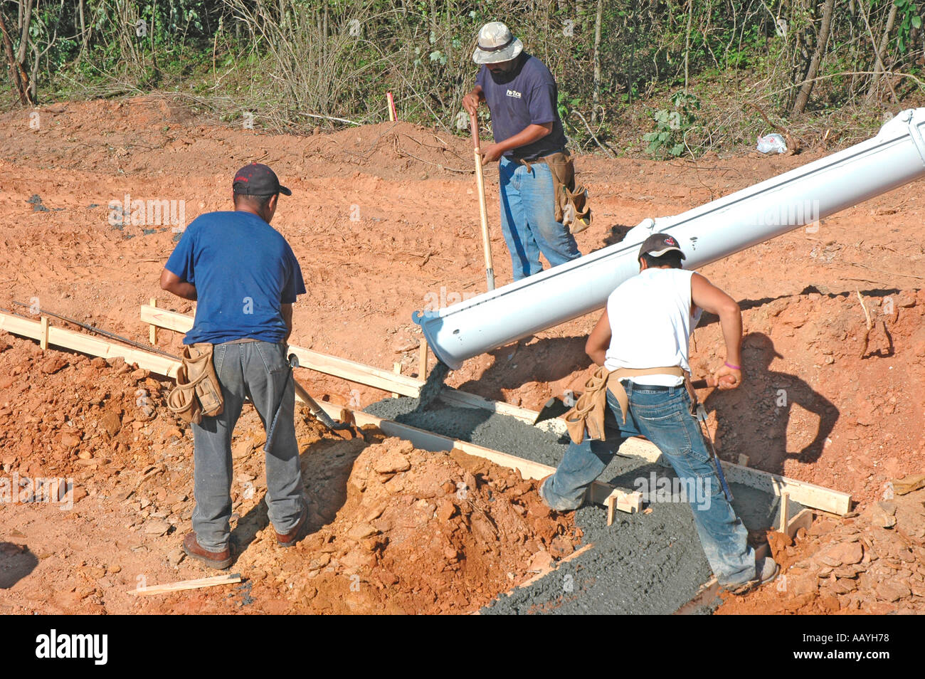 Putting in Cement footings for walls of new house by Latin labor laborers with delivery truck