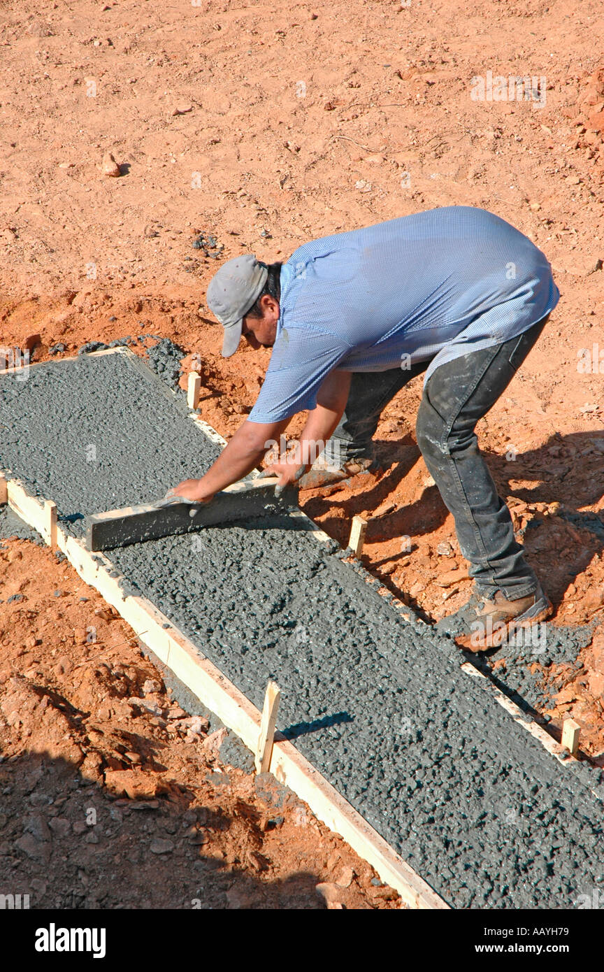 Putting in Cement footings for walls of new house by Latin labor laborers with delivery truck