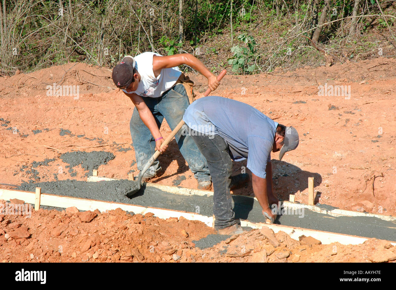 Putting in Cement footings for walls of new house by Latin labor laborers with delivery truck