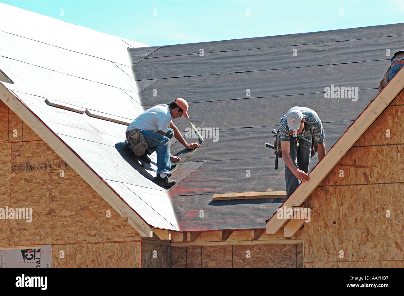 Installing vinyl siding new home construction on ladder using nail gun chop saw tape measure