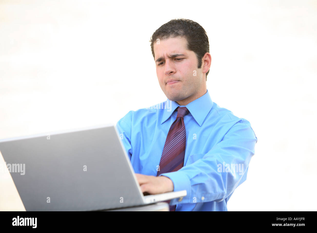 Young businessman working on laptop with frustrated look on face Stock Photo