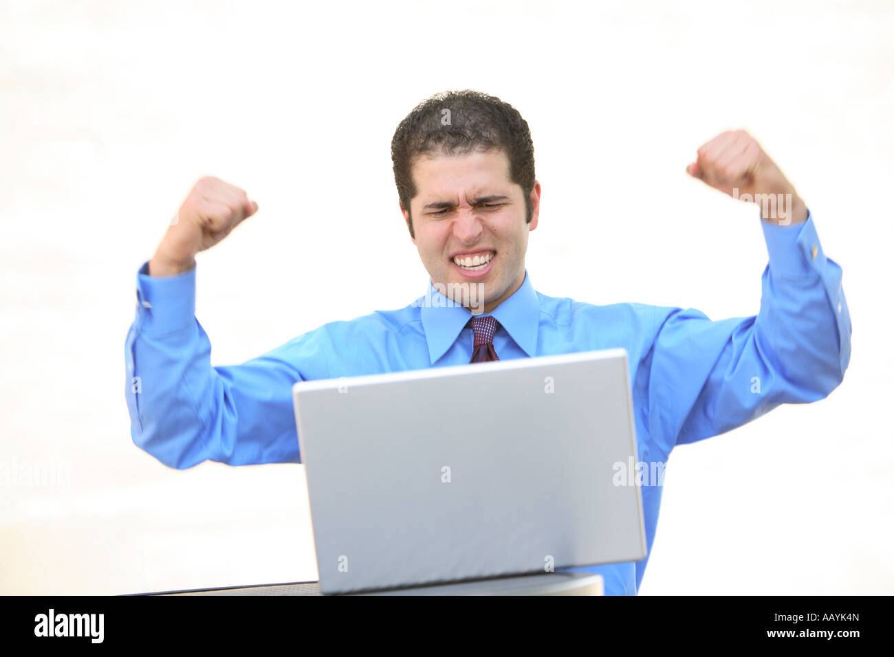 Businessman at laptop with arms in the air Stock Photo