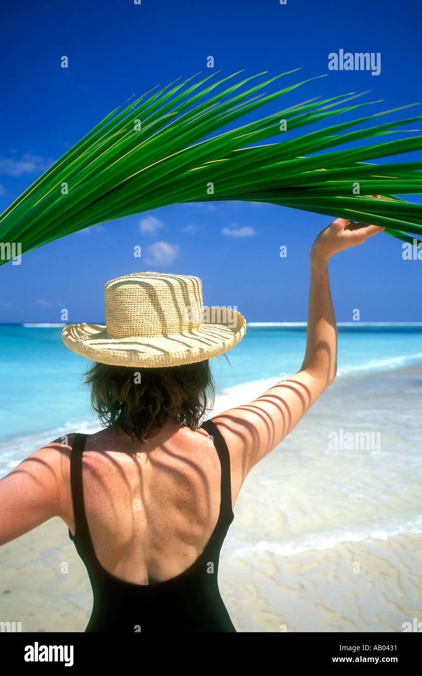Woman in swimsuit holding palm frond leaf overhead for shade Lombok Island Indonesia Southeast Asia Model released image Stock Photo
