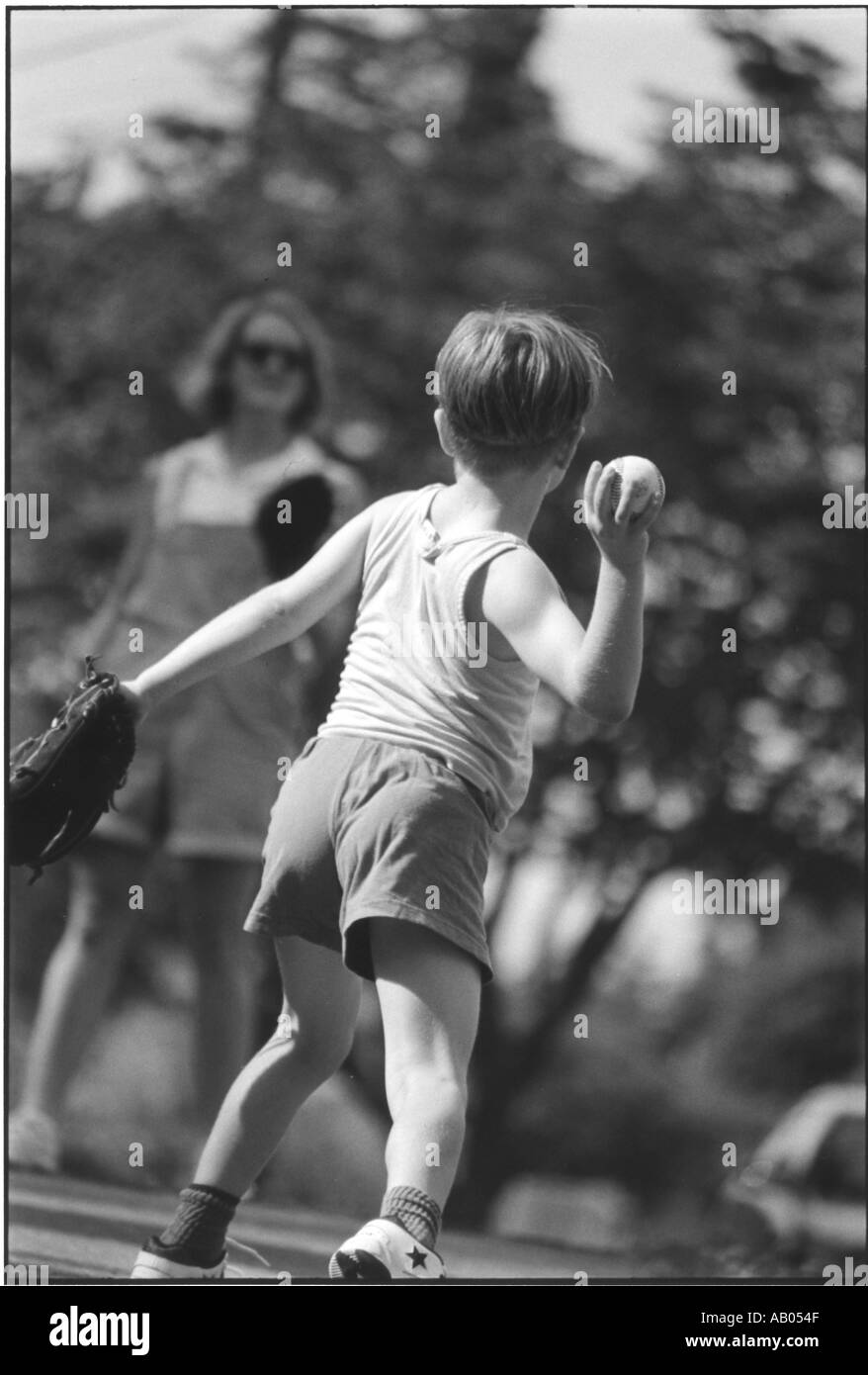 Young boy throwing baseball with his mother Stock Photo