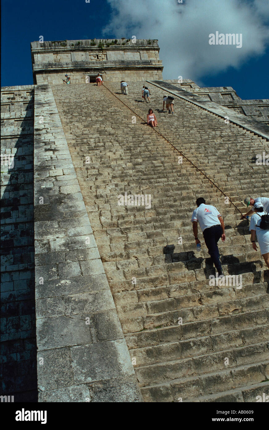 Visitors climbing the steps on the side of pyramid ruins at Chichen