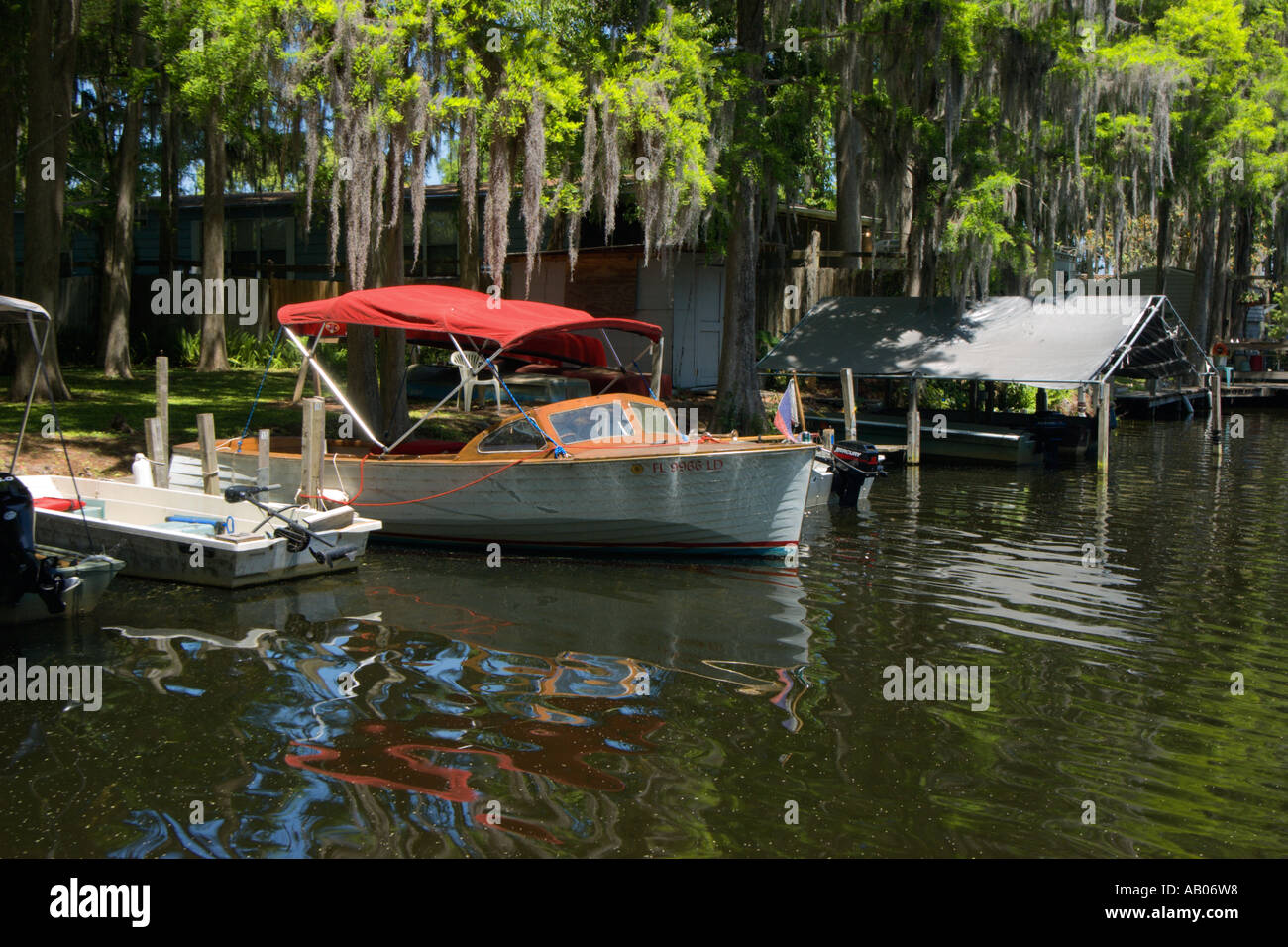 Wooden boat docked under cypress trees with spanish moss in the marina ...