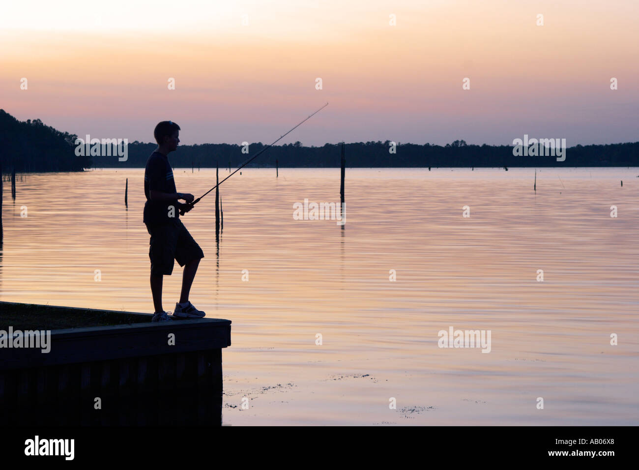 Silhouette of teenaged boy fishing off dock at Lake Rousseau Resort