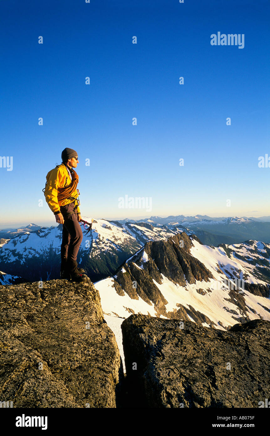Mountain climber holding an ice ax stands on the summit and looks out