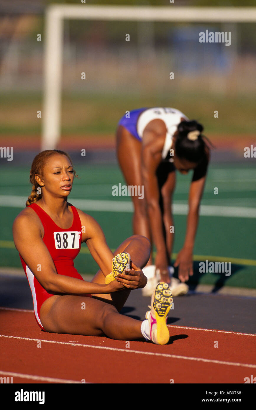 Two African American women track runners stretch before the start of