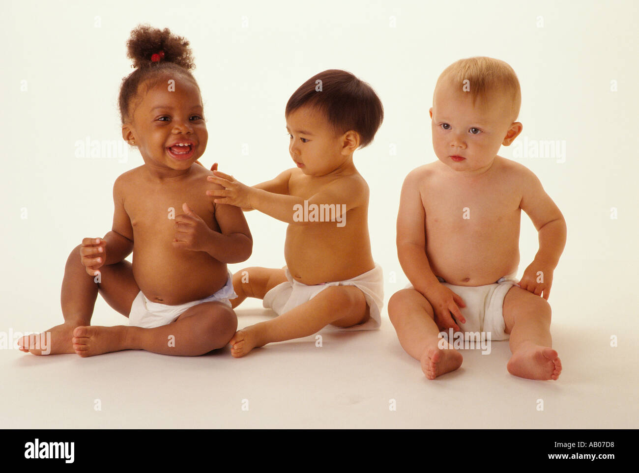 Three babies one black one white one Asian sit together in a ...