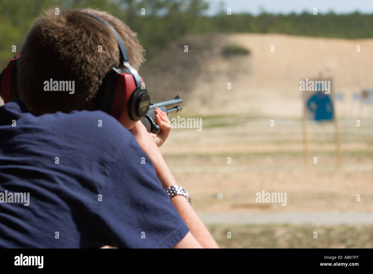 Male teenaged youth aims rifle during target practice at firing range in Ocala National Forest Ocala Florida USA Stock Photo