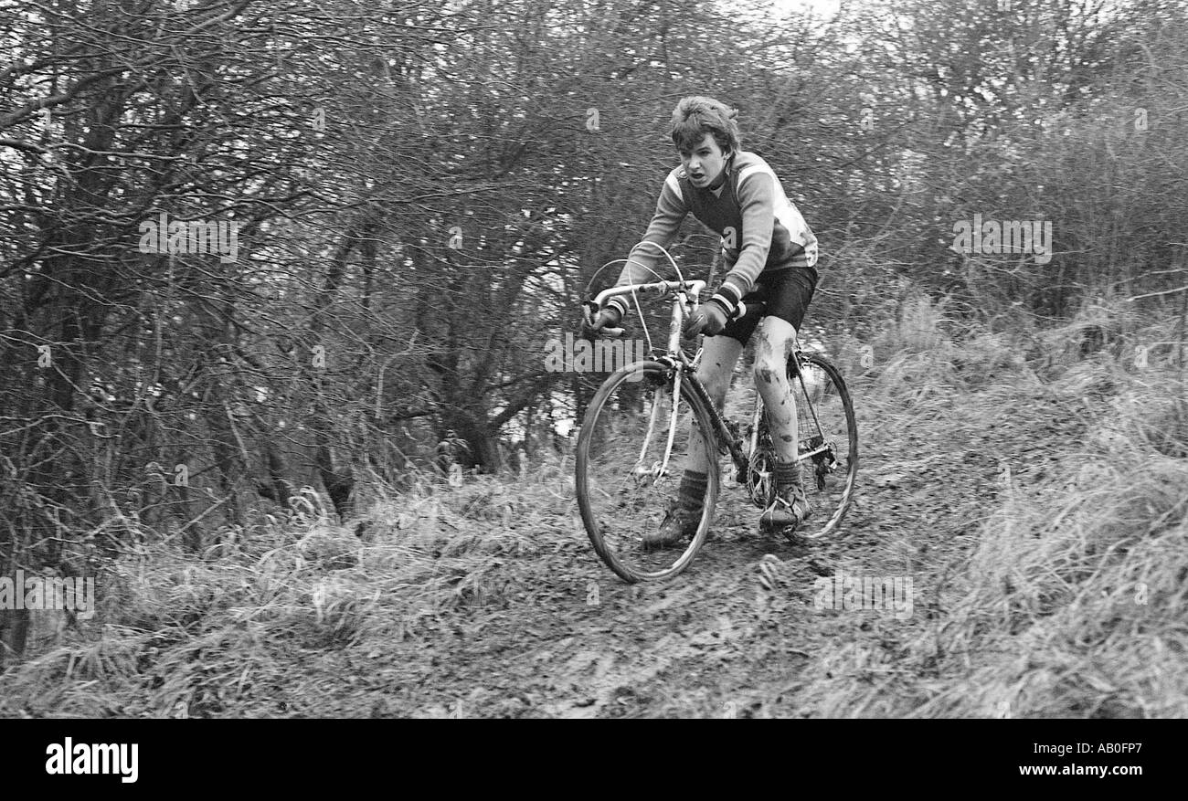 Young male cyclist in cross country bike race under wet and muddy conditions. Stock Photo