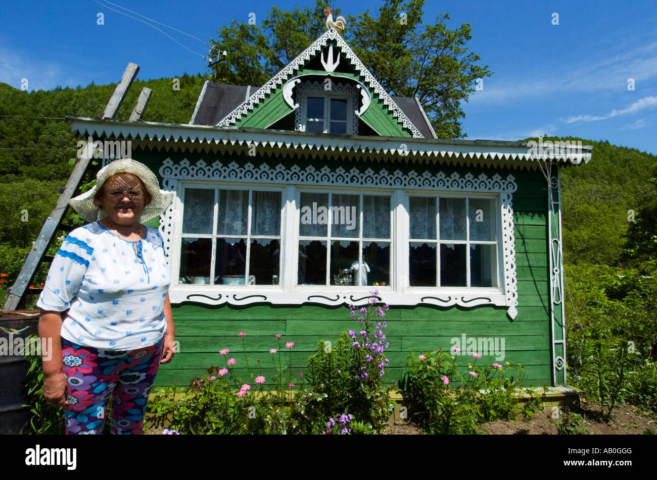 Woman stands outside her beautiful wooden dacha cottage in Sakhalin ...