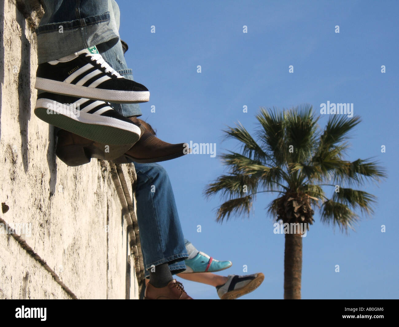 close up of people's feet sitting on wall by spanish steps in rome