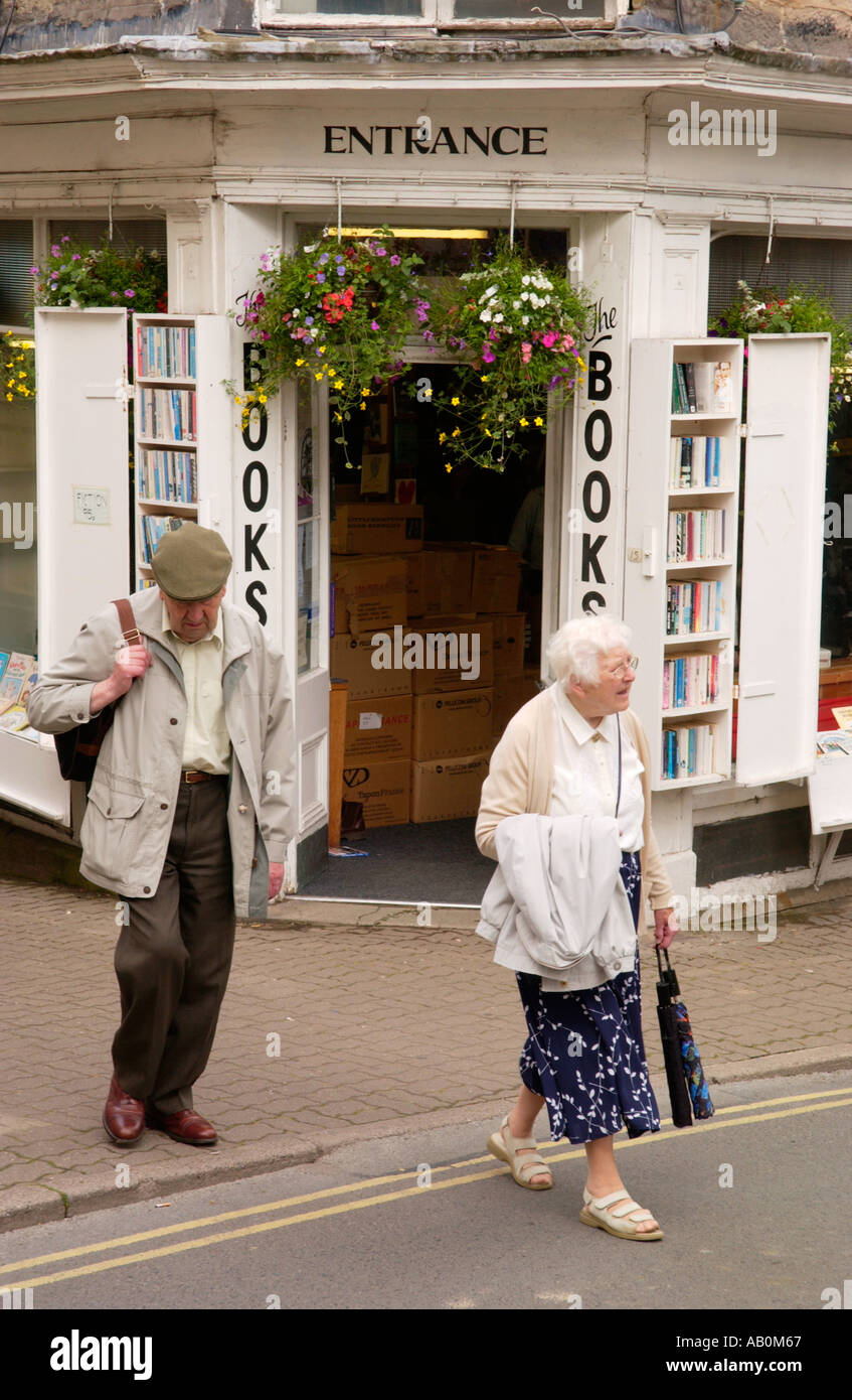 Elderly couple crossing road outside bookshop at Hay-on-Wye Powys Wales UK Stock Photo