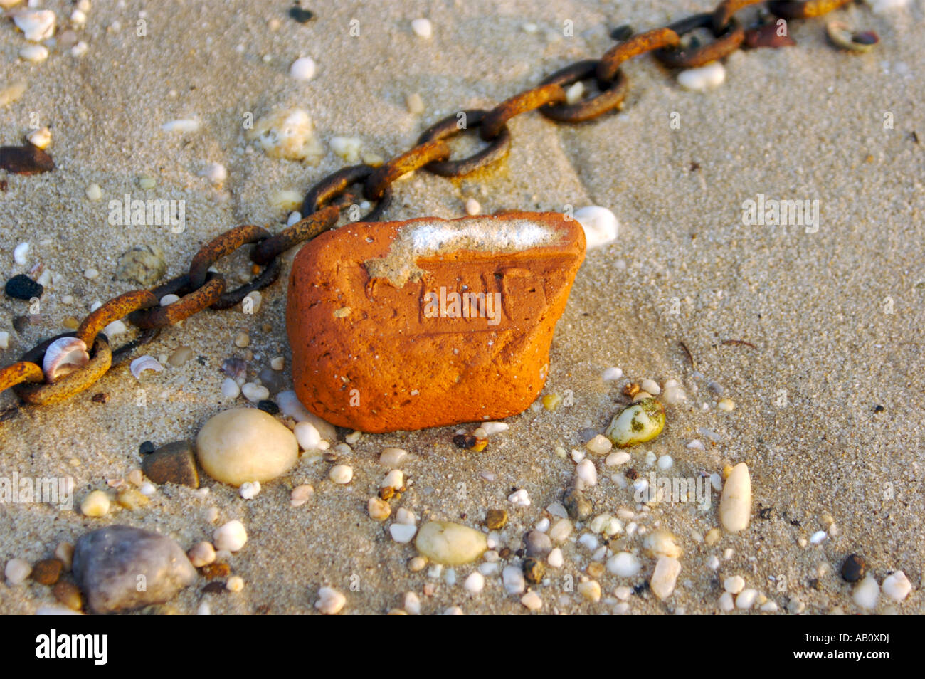 Rotten chain and brick on the beach Stock Photo