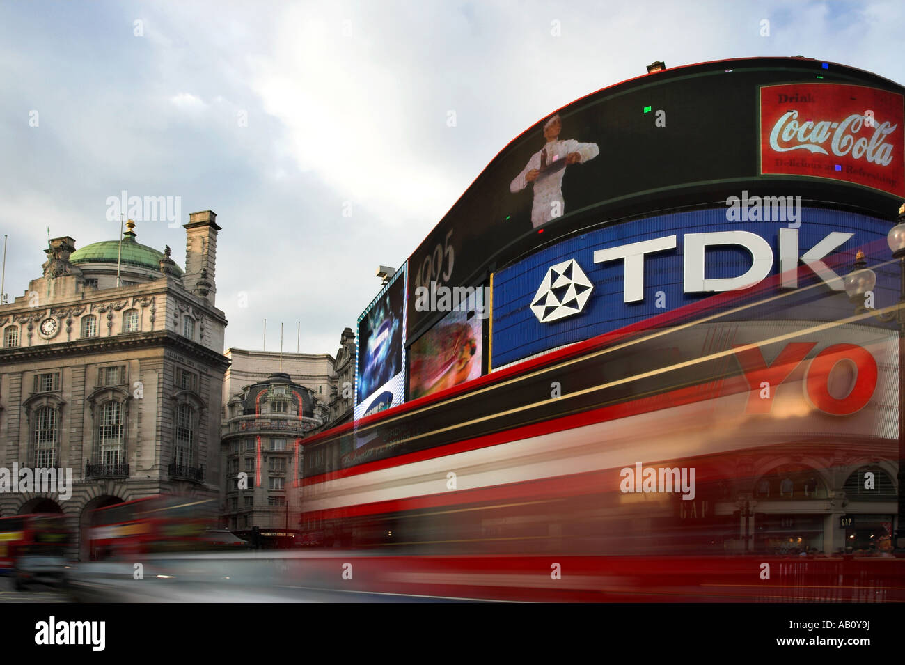 Picadilly Circus, London with bright billboards and red double decker bus blurred in foreground. Stock Photo