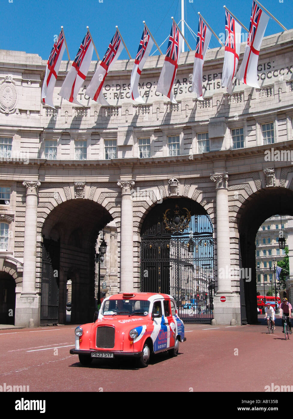 London Taxi coloured in the Union Jack flag with white ensign flags flying above on the Admiralty Arch, The Mall, London, England, United Kingdom Stock Photo