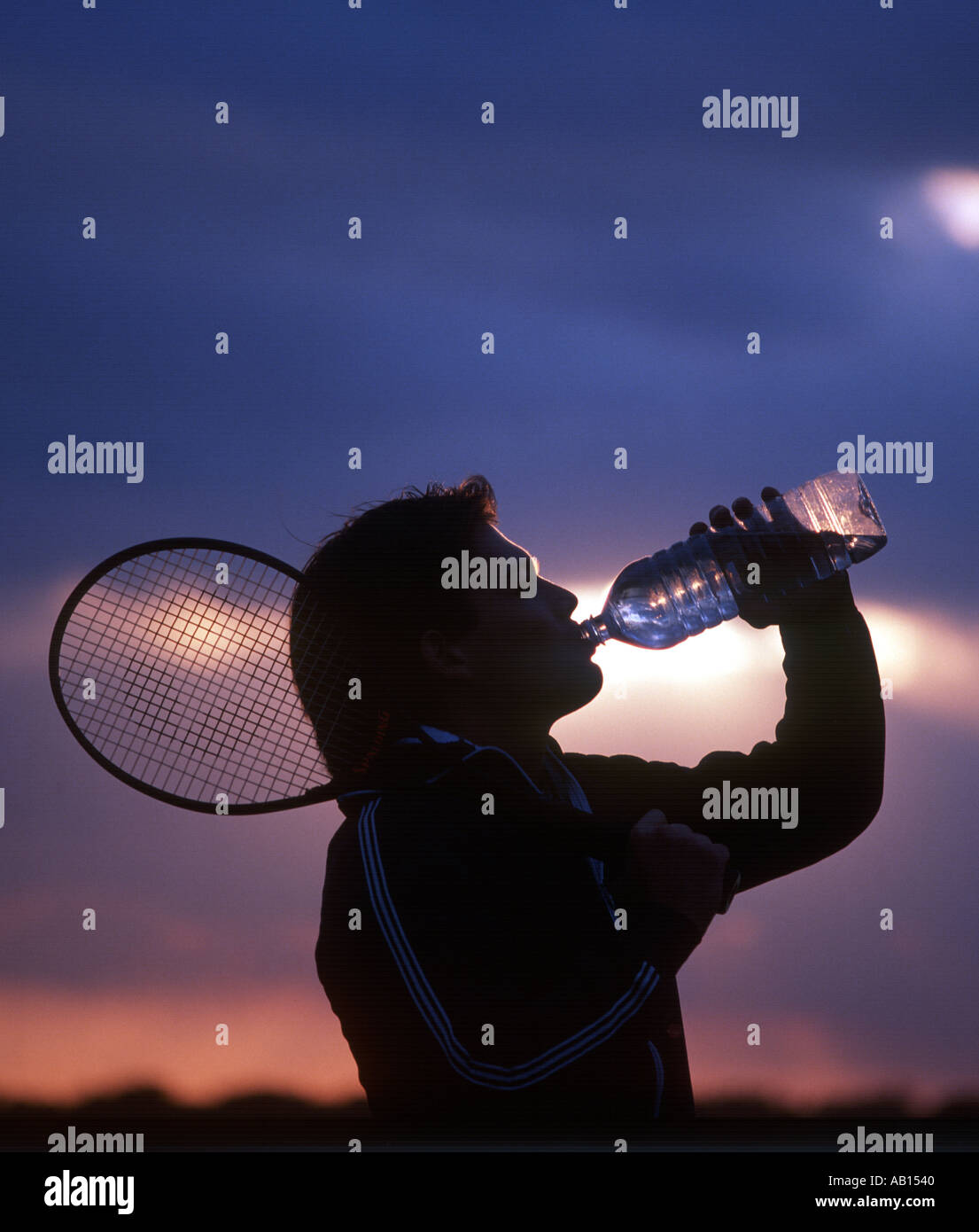 tennis player drinking water at sunset Stock Photo