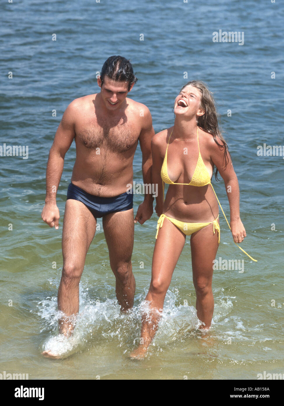 laughing couple emerging from the water after a swim Stock Photo