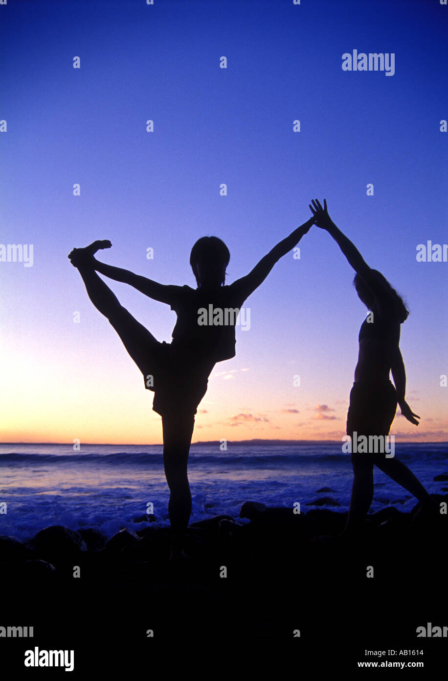 1327 Yoga in Noosa Queensland Woman in yoga position on rocky shore at dusk outdoor Stock Photo