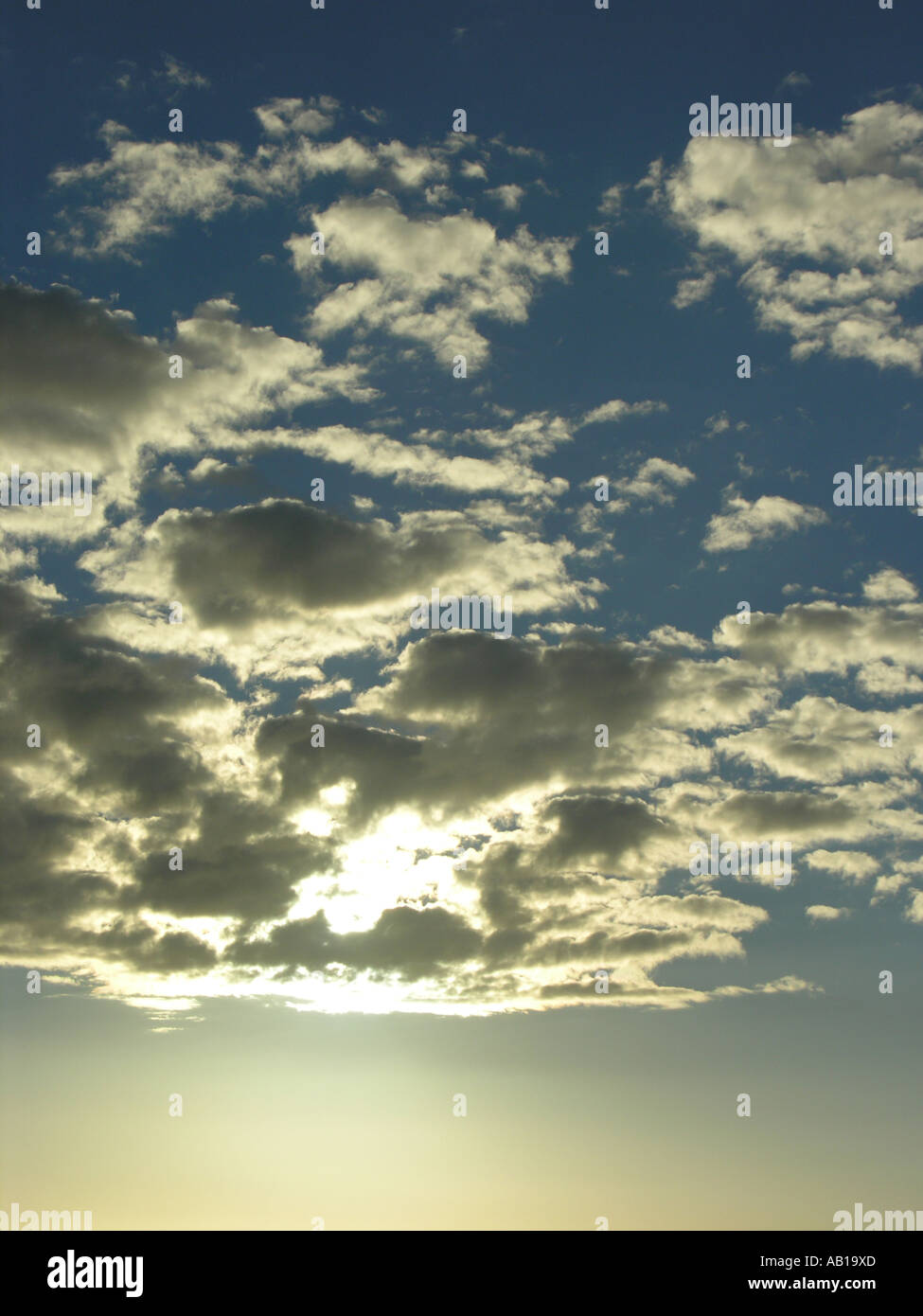 Sun peeking through loose cloud at daybreak Stock Photo