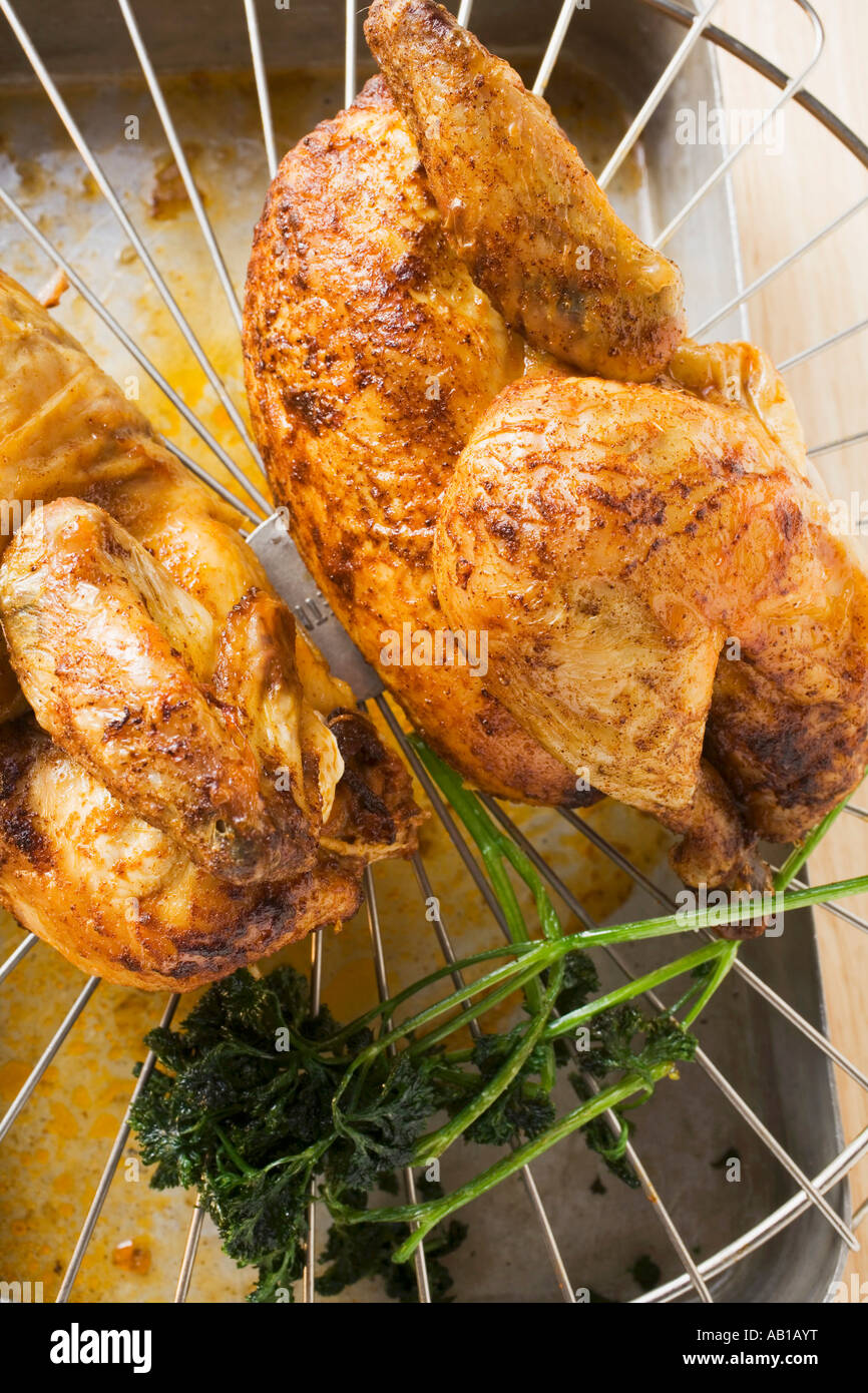 Two half roast chickens on rack above roasting tin FoodCollection Stock