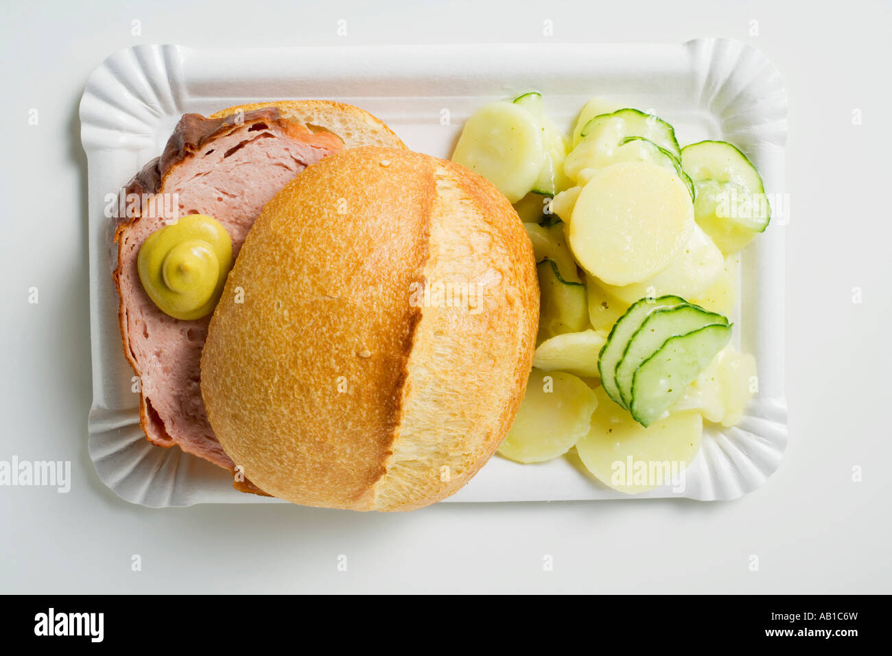 Leberkäse in roll with mustard potato salad on paper plate ...