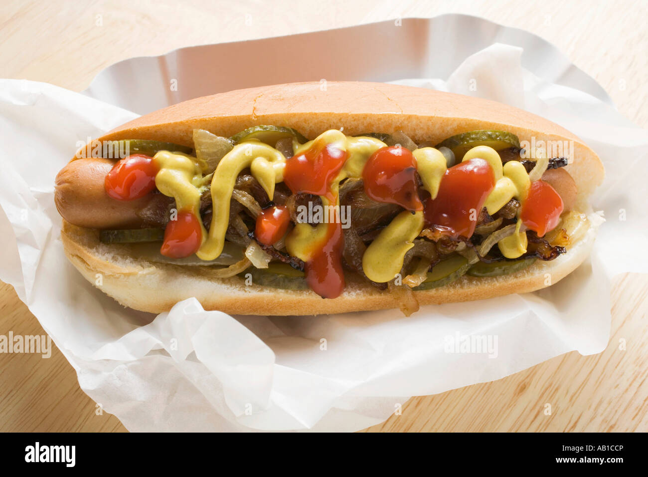 Hot dog with mustard ketchup gherkins and onions FoodCollection Stock