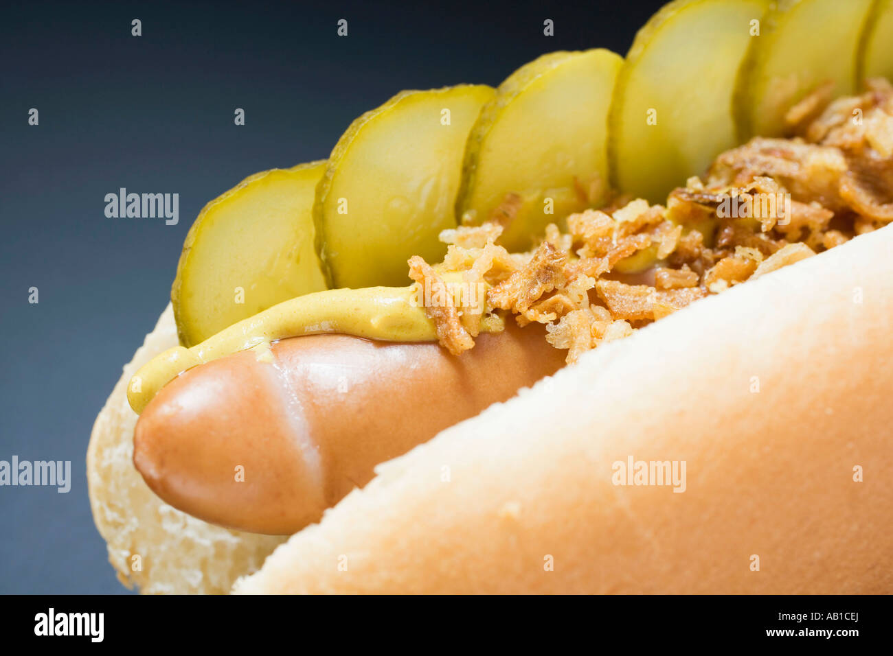 Hot dog with gherkins fried onions and mustard close up FoodCollection