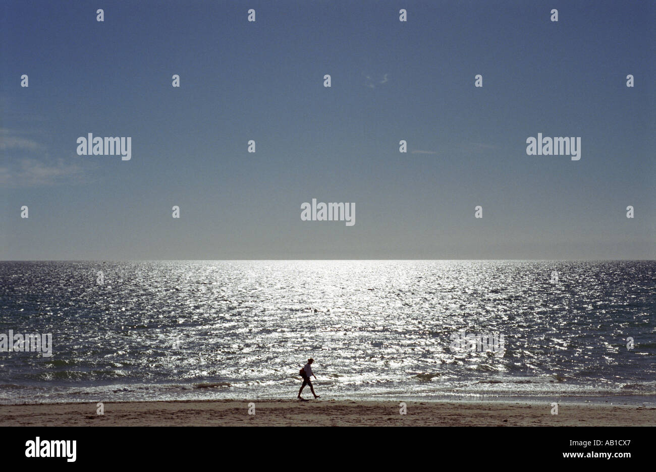 Man carrying backpack walking on beach Stock Photo - Alamy