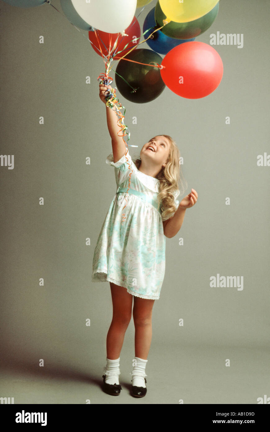 Young girl holding bunch of balloons Stock Photo