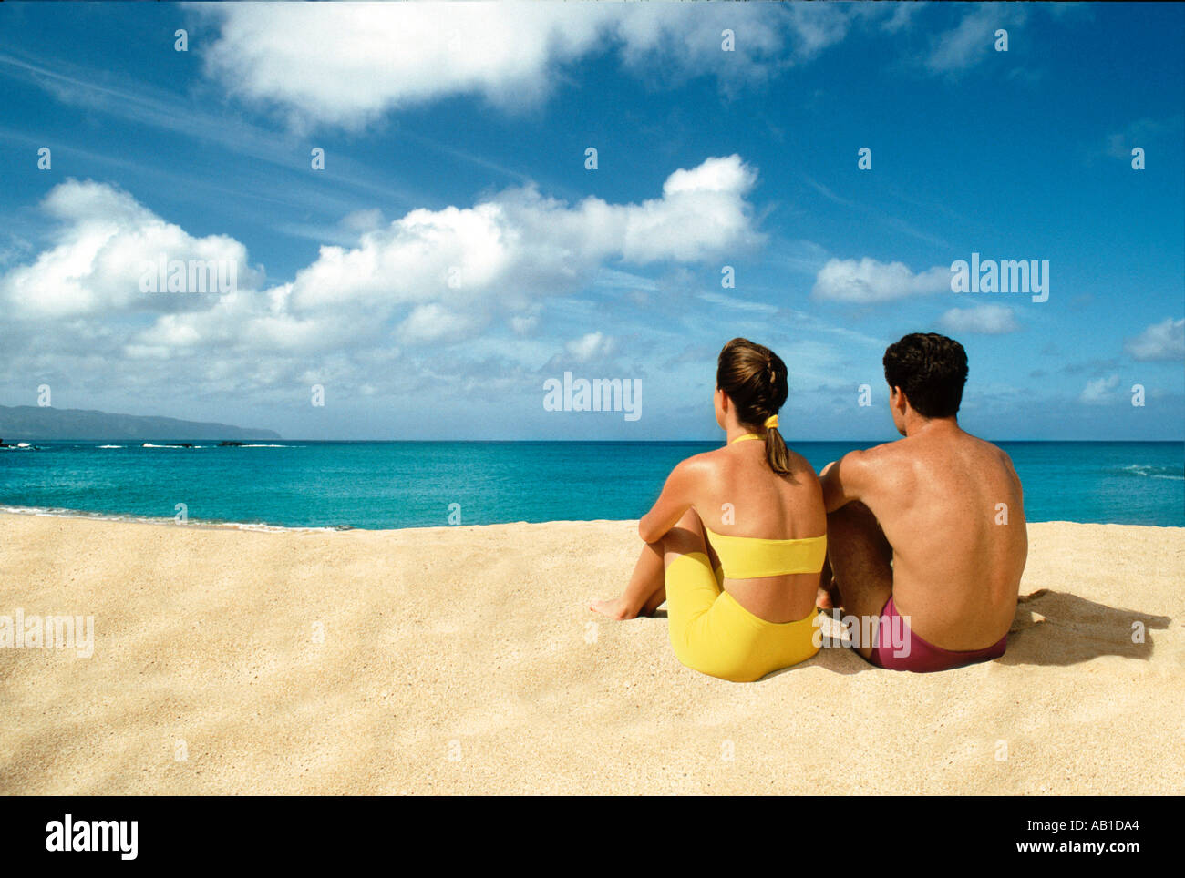 Couple sitting on beach looking to sea Stock Photo