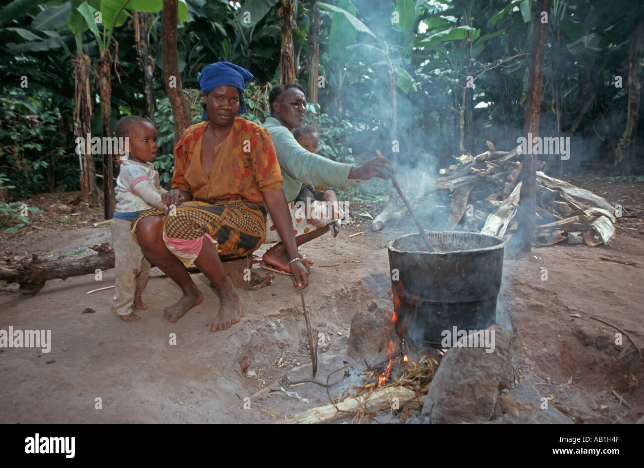 Women of the Chagga tribe with children cooking on the traditional three stone open fire, Kilimanjaro region, Tanzania Stock Photo