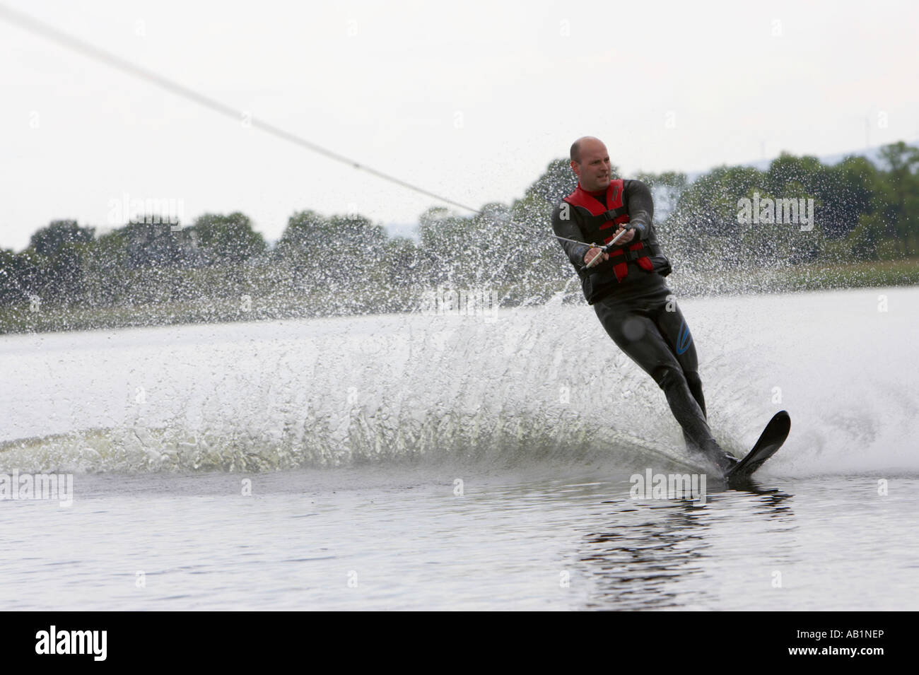 mid 30s waterskiing about to make a turn creating a wall of water behind and looking for obstacles Stock Photo