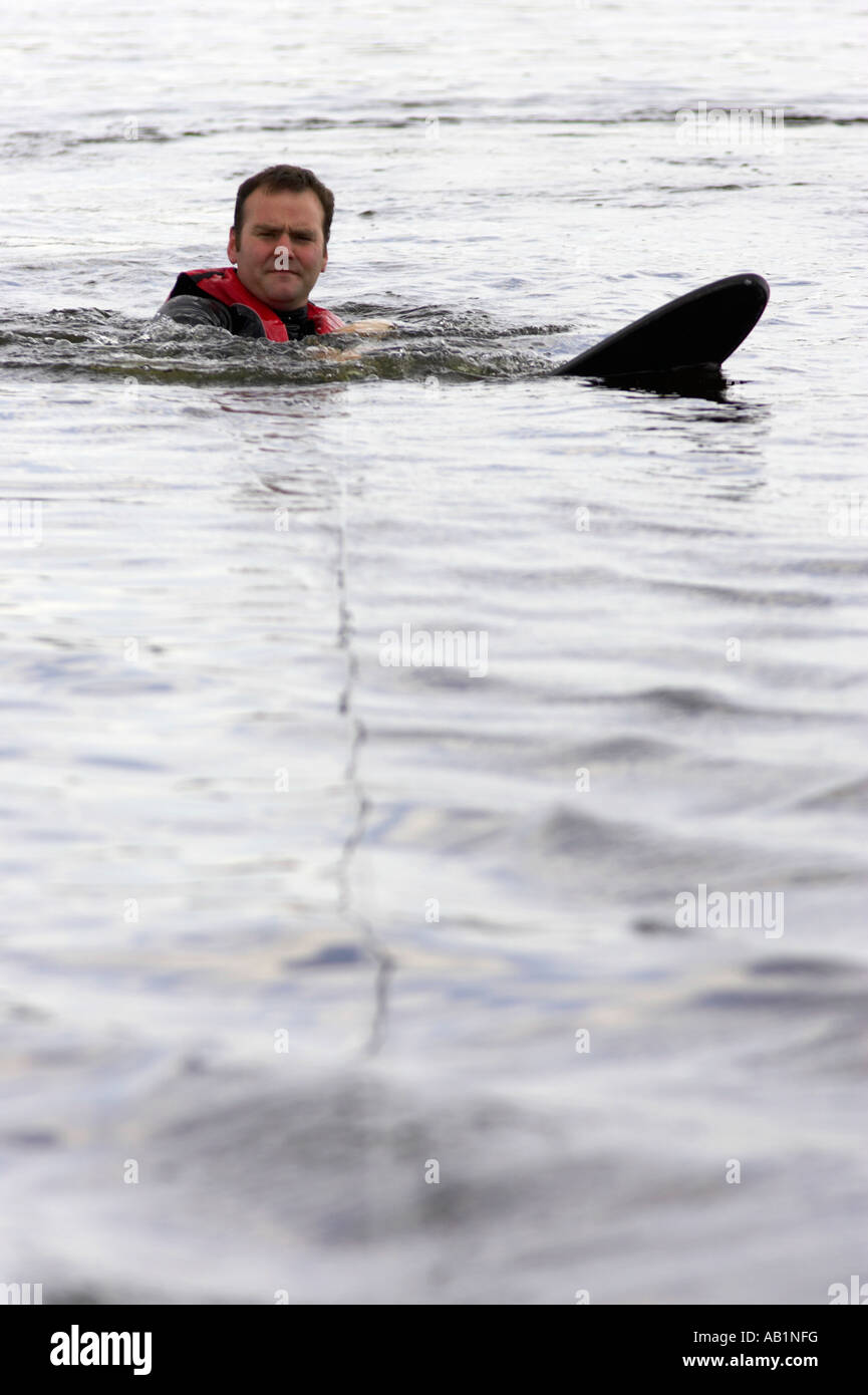 mid 30s male in wetsuit with water ski attached floating in the water