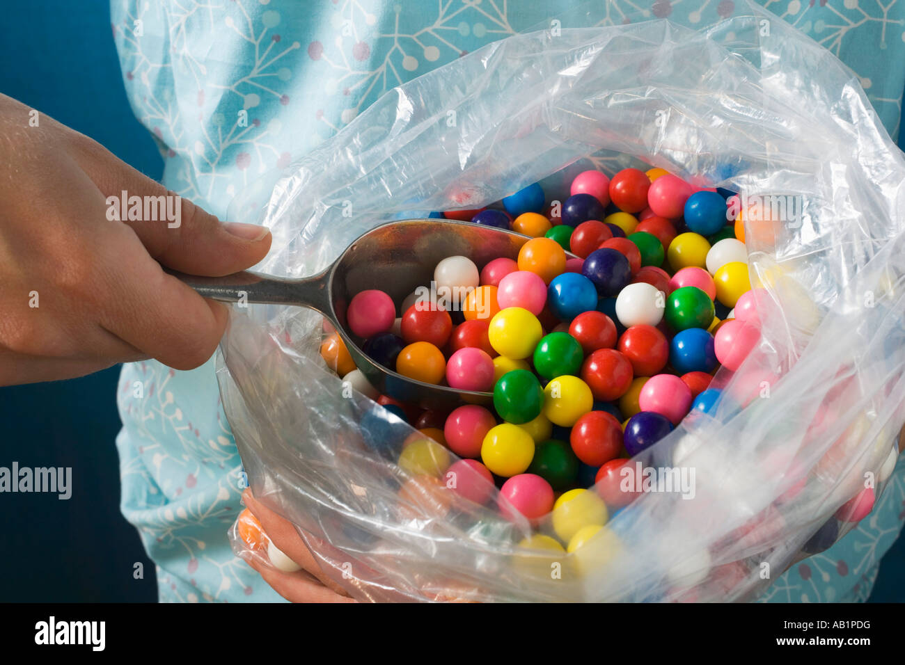 Hand taking bubble gum balls out of plastic bag with scoop FoodCollection Stock Photo