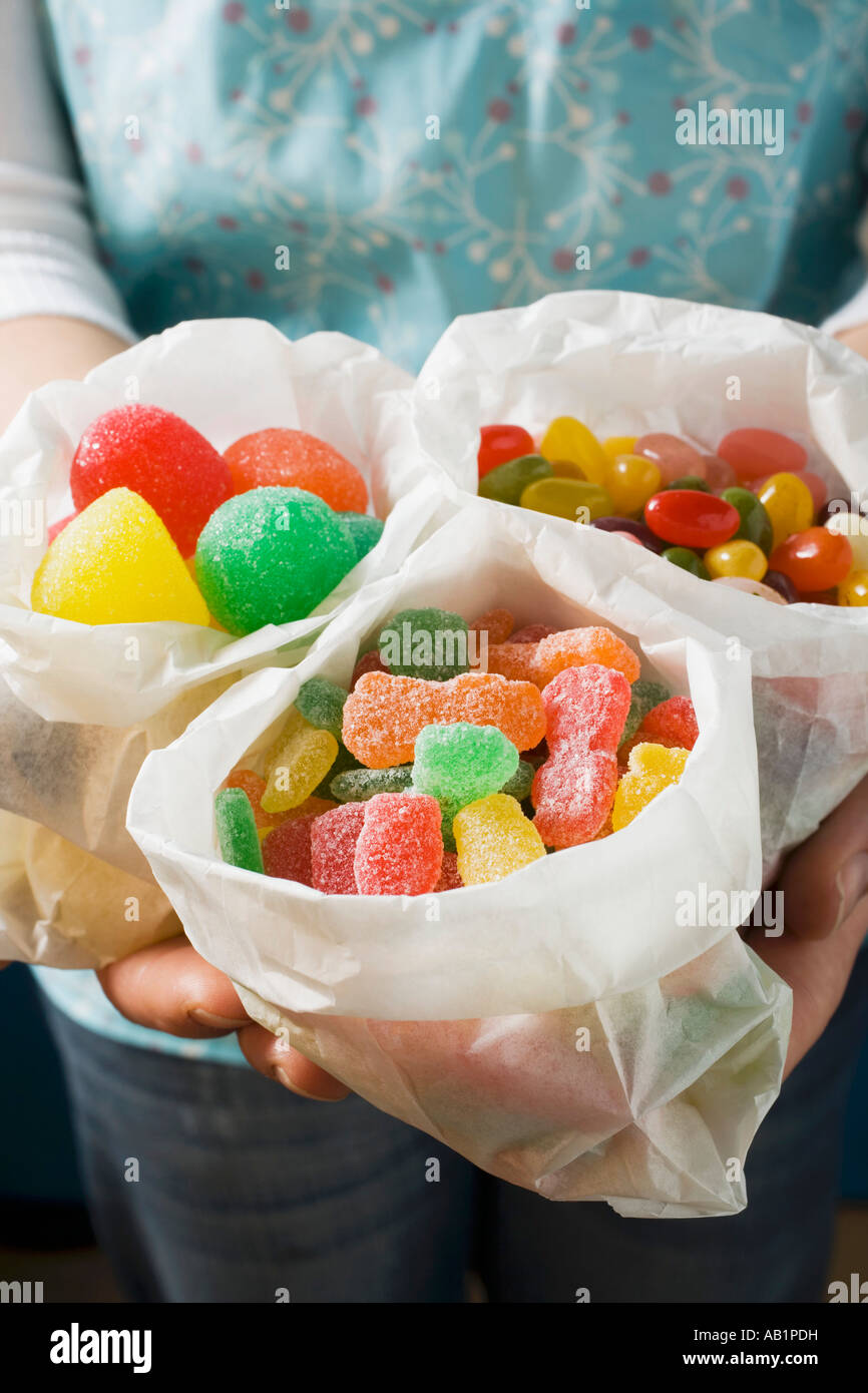 Hands holding three paper bags of jelly sweets FoodCollection Stock
